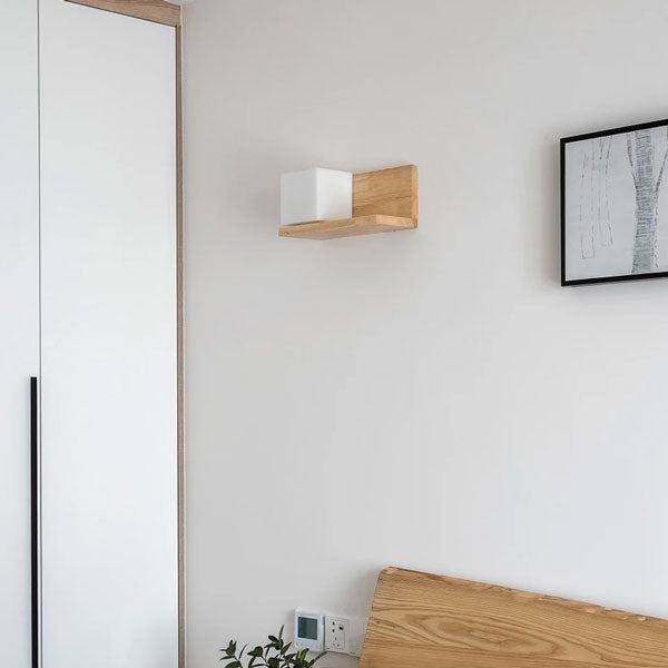 Applique murale design en bois et verre installée dans une chambre